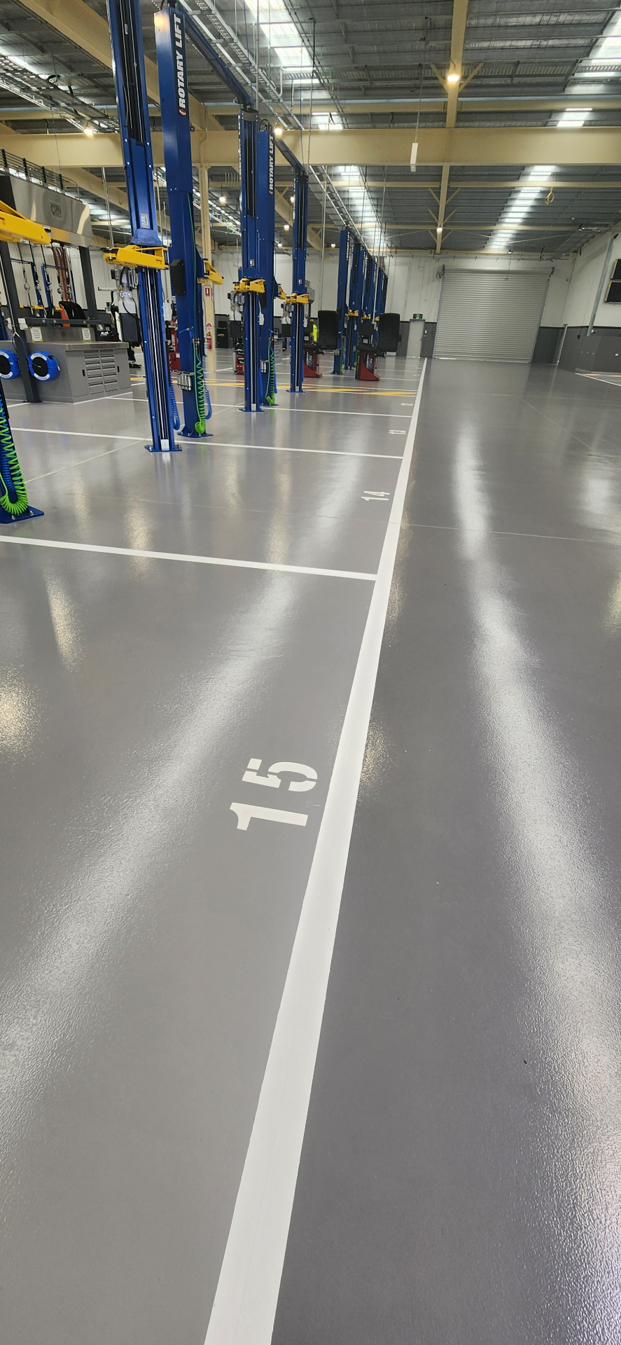 Grey workshop floor with white numbered industrial bay markings