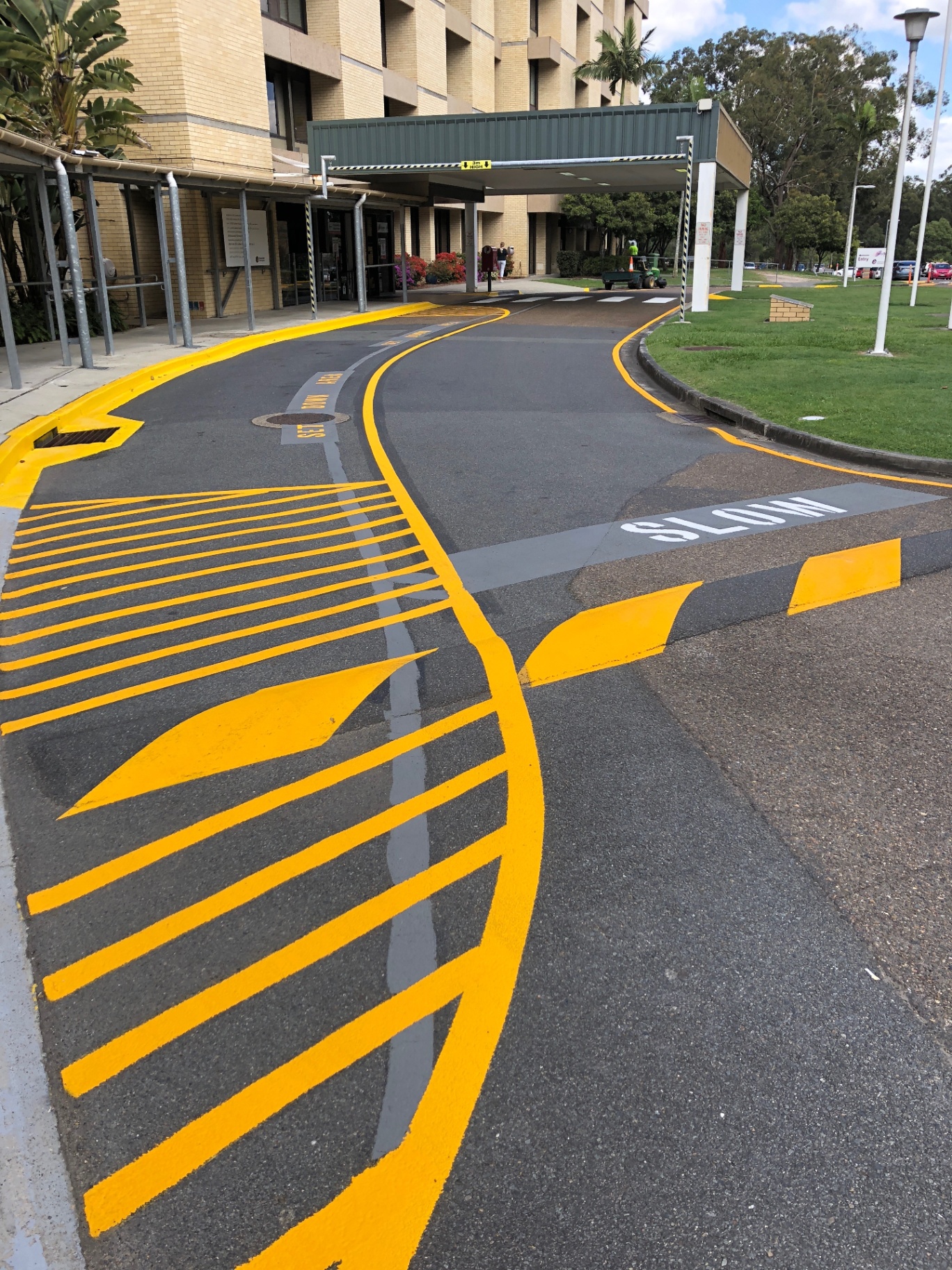 Yellow hatched no-stopping zone and SLOW marking at hospital driveway