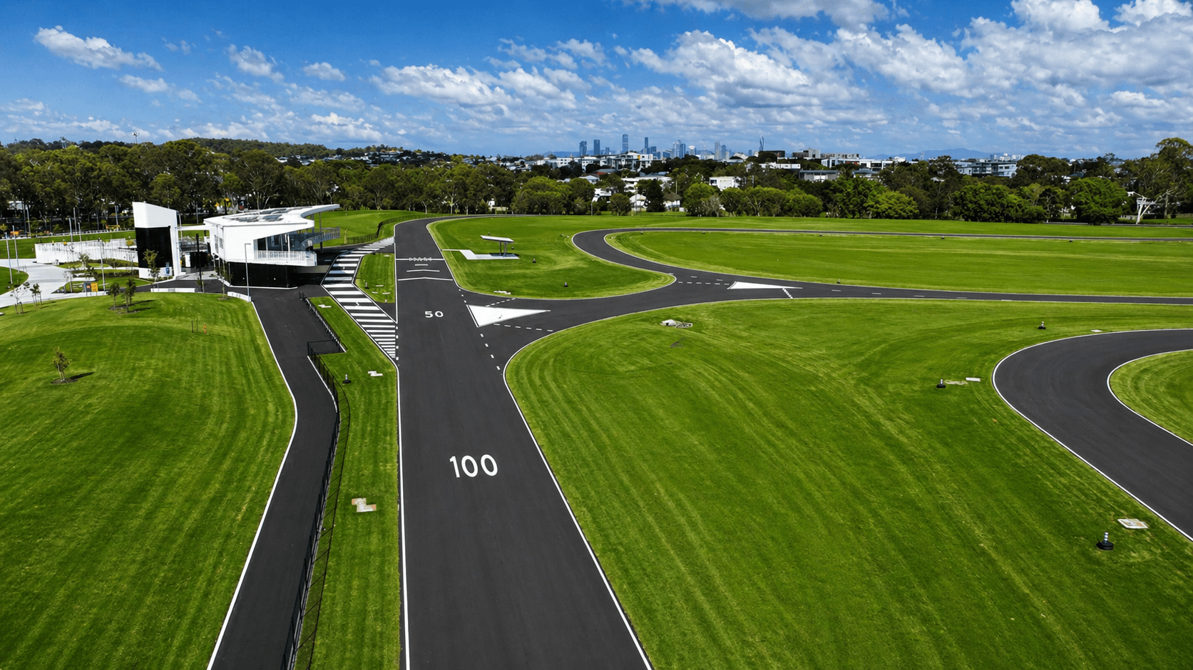 Aerial view of driver training track with fresh line markings and Brisbane skyline